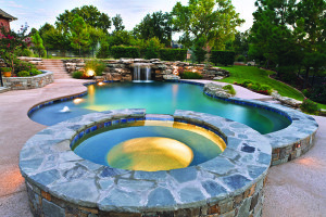 A beautiful pool design by Ewing Aquatech enhanced by ambient pool lighting.